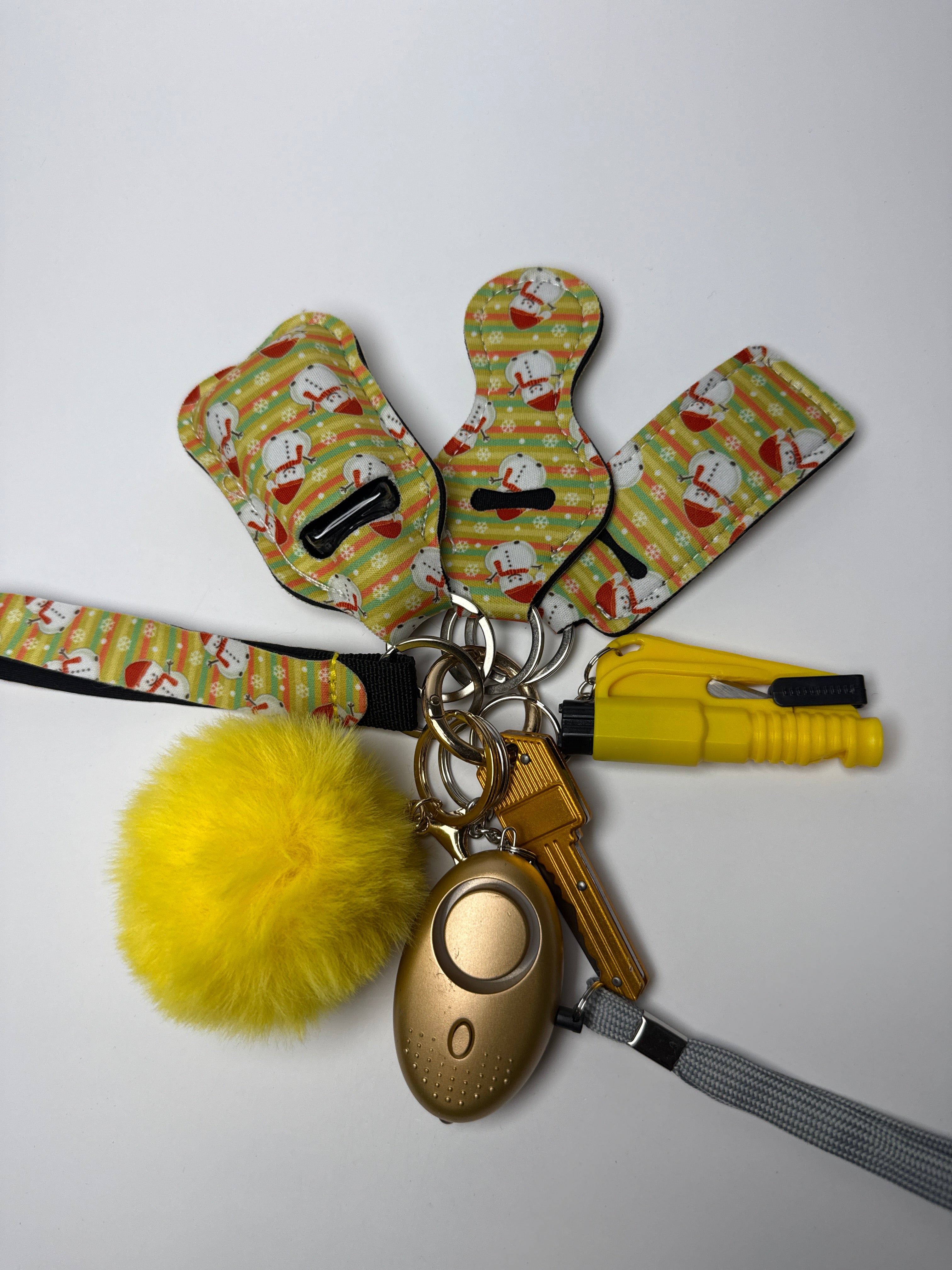 Santa stripe wristlet keychain set with yellow pom charm, compact personal alarm, and mini light on a white background.